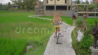一个年轻的女人骑着自行车穿过美丽的稻田。 前往<strong>东南亚</strong>的概念。 慢镜头